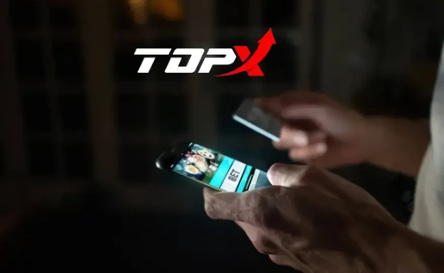 Mãos segurando um celular, com o logotipo da TopX ao fundo